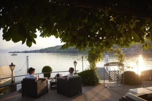 two people sitting in chairs on a patio by the water at Hotel Restaurant Seehof in Küssnacht
