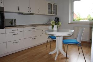 a white kitchen with a table and two chairs at Schwabe, Ferienwohnung in Schneverdingen