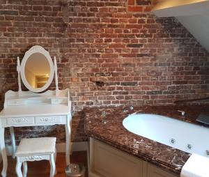 a bathroom with a brick wall and a bath tub at Hotel Recour in Poperinge