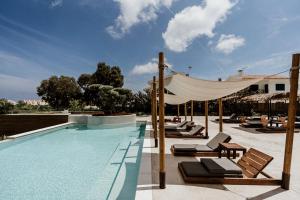 een zwembad met ligstoelen en een luifel bij Cavo Zoe Seaside Hotel in Protaras