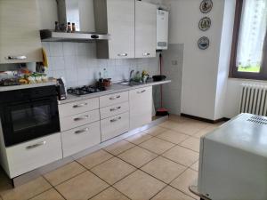een keuken met witte kasten en een fornuis met oven bij Rod Ranch Livestock - Appartamento con camino e vista piscina in Campagnano di Roma