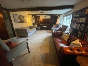 uma sala de estar com sofás de couro e um piano em Seatoller House em Borrowdale Valley