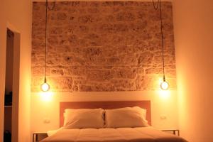 1 dormitorio con pared de ladrillo y 1 cama con 2 luces en Domus Bama, en Ceglie Messapica
