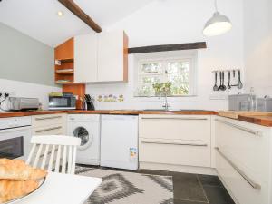 a white kitchen with a sink and a dishwasher at Great Brightor Cob Barn in Bodmin
