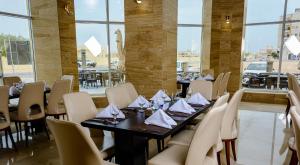 uma sala de jantar com mesas, cadeiras e janelas em Bristol Hotel Salalah em Salalah