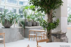 a room with tables and chairs and plants at KIRO Hiroshima by THE SHARE HOTELS in Hiroshima