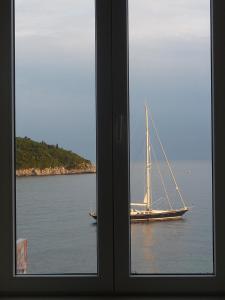 un velero en el agua visto desde una ventana en Banje Beach Oasis Apartment en Dubrovnik