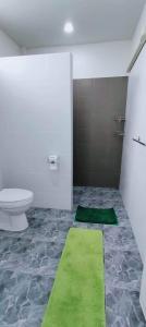 a bathroom with a toilet and a green rug at Poonsap Homestay in Nan
