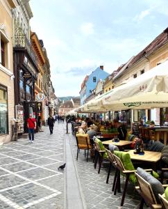 a street with tables and chairs and people walking down the street at Republique Apartment in Braşov