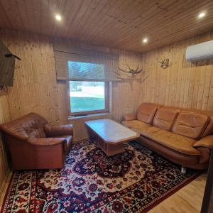 una sala de estar con 2 sofás de cuero y una mesa. en Домик с сауной для отдыха en Katase