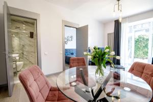 a dining room with a glass table and pink chairs at New apartment LOFT MAJORI with terrace in Jūrmala