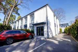 een rode auto geparkeerd voor een wit gebouw bij New apartment LOFT MAJORI with terrace in Jūrmala