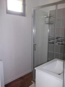 La salle de bains blanche est pourvue d'une douche et d'un lavabo. dans l'établissement Charmante maison Lotoise, à Bretenoux