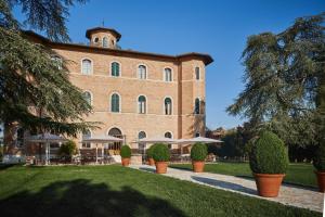 un grand bâtiment en briques avec des parapluies devant lui dans l'établissement Precise Tale Poggio Alla Sala, à Montepulciano