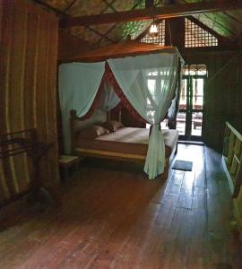 a bedroom with a bed with a mosquito net at Happy Ria Homestay & Guesthouse in Bukit Lawang
