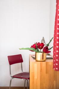 una mesa con una silla roja y un jarrón con flores rojas en Landhaus Alger, en Immenstadt im Allgäu