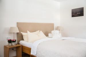 1 dormitorio con 1 cama con sábanas y almohadas blancas en Landhaus Alger, en Immenstadt im Allgäu