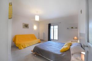 een slaapkamer met een bed en een gele deken bij Le Mas Saint Pierre - 10 personnes in Cabannes