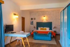 Schlafzimmer mit einem Bett mit einem blauen Stuhl und einem Schreibtisch in der Unterkunft StayVista at Tulip Terraces in Manali