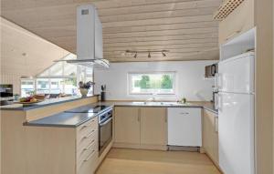 a kitchen with a white refrigerator and a sink at Beautiful Home In Væggerløse With Sauna in Marielyst