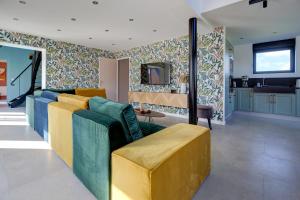 sala de estar con sofá y TV en Un nid dans la Grange - Maison avec jacuzzi et sauna 