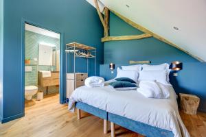 1 dormitorio azul con 1 cama y baño en Un nid dans la Grange - Maison avec jacuzzi et sauna 