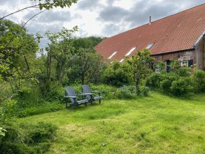 two benches sitting in the grass next to a house at Ferienhof Spiegelhaus in Krummhörn