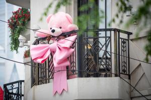 um urso de peluche cor-de-rosa sentado numa varanda com um laço rosa em The Yangtze Boutique Shanghai - Free minibar for the first round of the day em Xangai