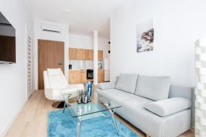 sala de estar con sofá blanco y mesa de cristal en Reymonta 22 Apartamenty en Opole