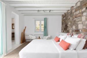 a bedroom with a white bed and a brick wall at El Sueno Villa Mykonos in Kalafatis