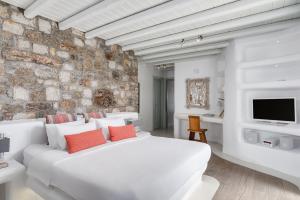 a bedroom with a white bed and a stone wall at El Sueno Villa Mykonos in Kalafatis