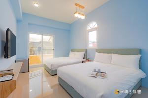 um quarto de hotel com duas camas e uma televisão em Tie Zhi Road B&B em Taitung City
