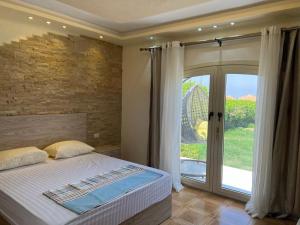 1 dormitorio con 1 cama y puerta corredera de cristal en Villa Front Beach First row family only en Ain Sokhna