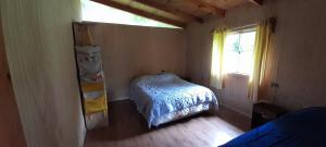 a small bedroom with a bed and a window at cabaña el descanso in Lago Ranco
