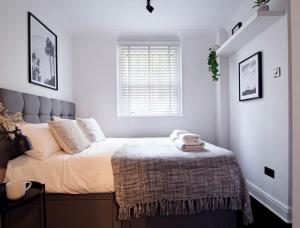 Luxury 2BR Flat in Hip Notting Hill في لندن: غرفة نوم بسرير وبطانية ونافذة