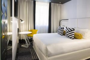 um quarto de hotel com uma cama e uma cadeira amarela em Hotel Ekta Champs Elysées em Paris