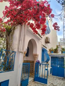 Coup de cœur à Sidi Bou Said في سيدي بو سعيد: مبنى ذو بوابات زرقاء وشجر به ورد احمر