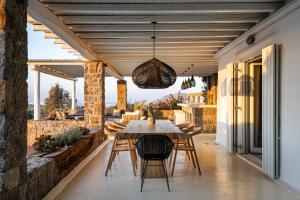 a dining room with a table and chairs on a patio at El Sueno Villa Mykonos in Kalafatis
