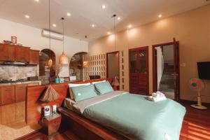 a bedroom with a large bed and a kitchen at Chaca Beach House in Da Nang