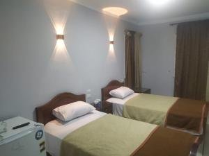 Cette chambre comprend 2 lits et des lumières sur le mur. dans l'établissement فندق هابى دريمز, au Caire