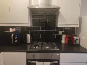 a kitchen counter with a stove and a microwave at Comfy Stay and Relaxing Apart in London