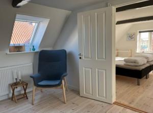 a bedroom with a bed and a blue chair and a door at Unik ferielejlighed i Marstal. in Marstal