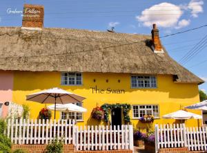 a yellow house with a thatched roof at The Swan Inn in Monks Eleigh