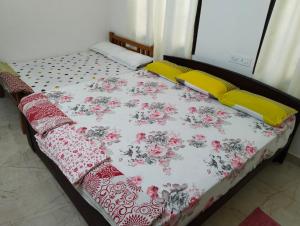 Una cama con colcha de flores y almohadas amarillas. en Tirunelveli Home Stay, en Tirunelveli