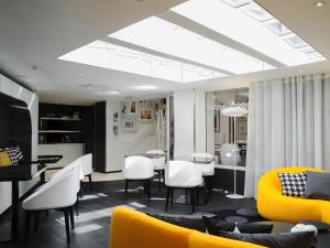 a living room with a yellow couch and white chairs at Hotel Ekta Champs Elysées in Paris
