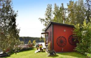 a red shed with a large wagon wheel on it at Beautiful Home In Finspng With Wifi in Finspång