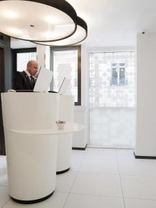 un homme assis à un bureau avec un ordinateur portable dans l'établissement Hotel Ekta Champs Elysées, à Paris