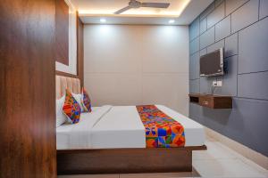 a bedroom with a bed and a tv on a wall at FabHotel Coral in Indore