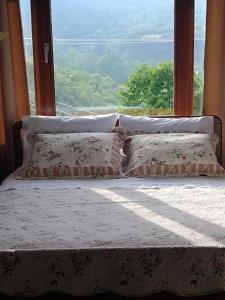 un letto con cuscini, posto di fronte a una finestra di ΖΕΦΥΡΟΣ a Litóchoron