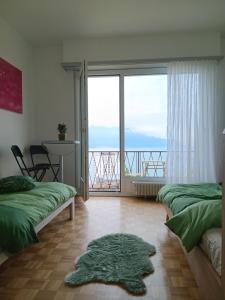 a room with two beds and a balcony with a view at La plus belle vue du lac Léman in Montreux